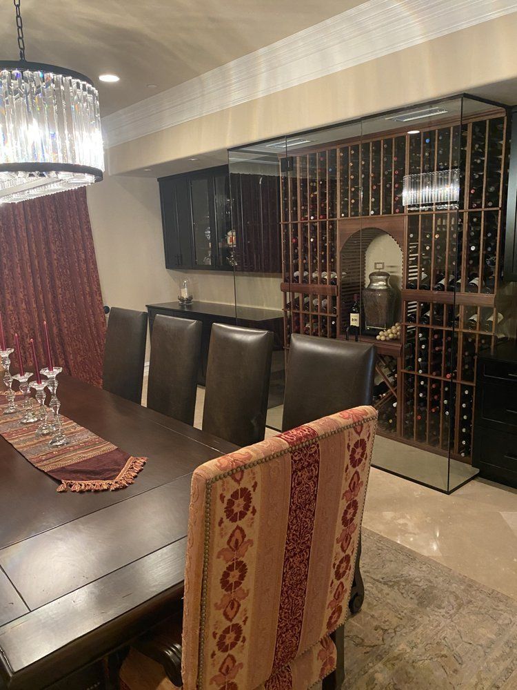 Dining room with dark wood table, chairs, and wine storage. Red accents, chandelier.