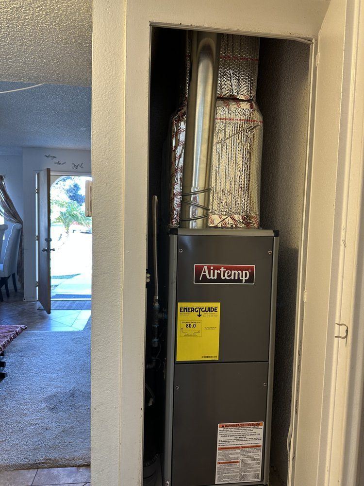 A furnace in a closet. The unit is silver with the 