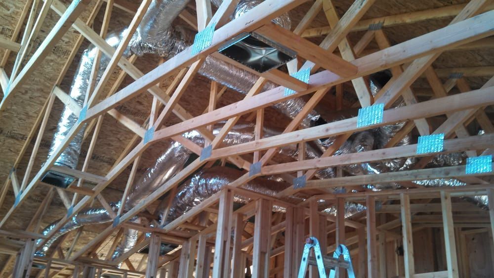 Wooden roof trusses under construction, with ductwork and metal connectors visible.