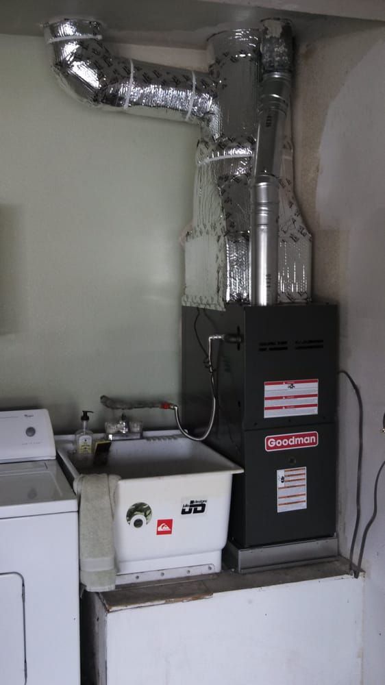 Furnace in a laundry room with a laundry sink and washing machine. Ductwork and electrical wiring are visible.