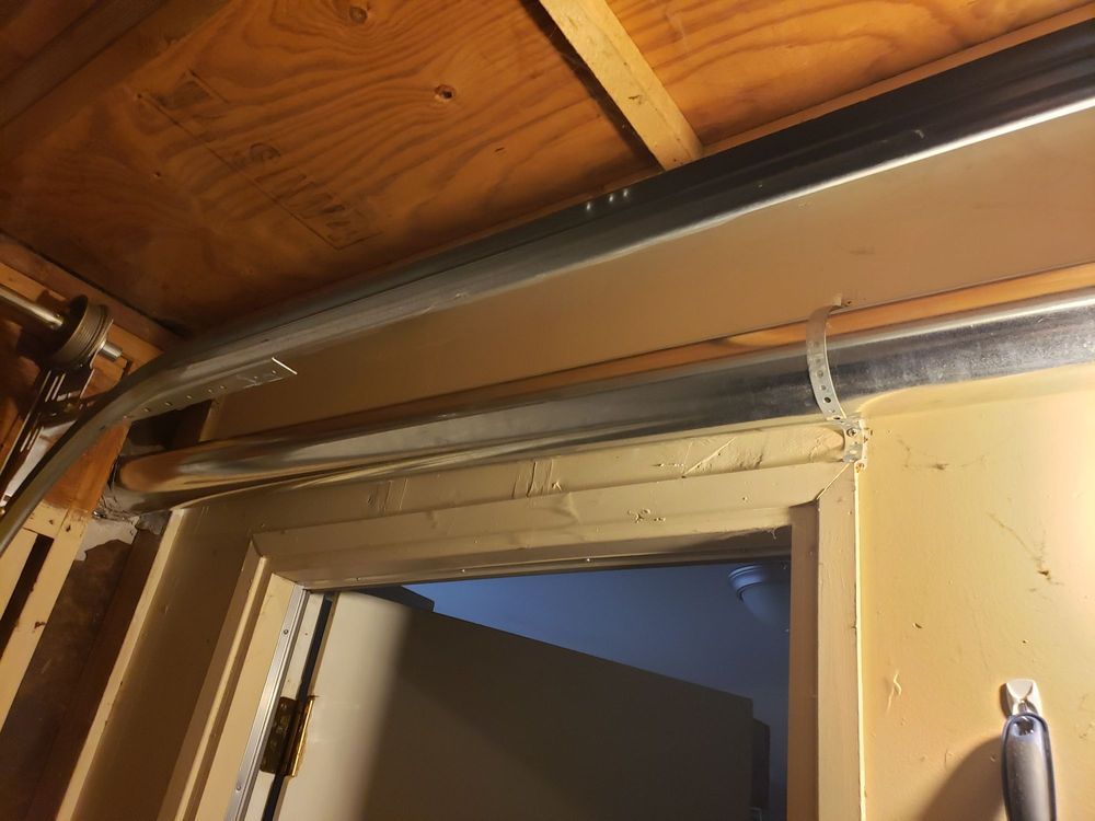 Garage door track and frame, view from inside the garage. Wood and metal construction, low angle.