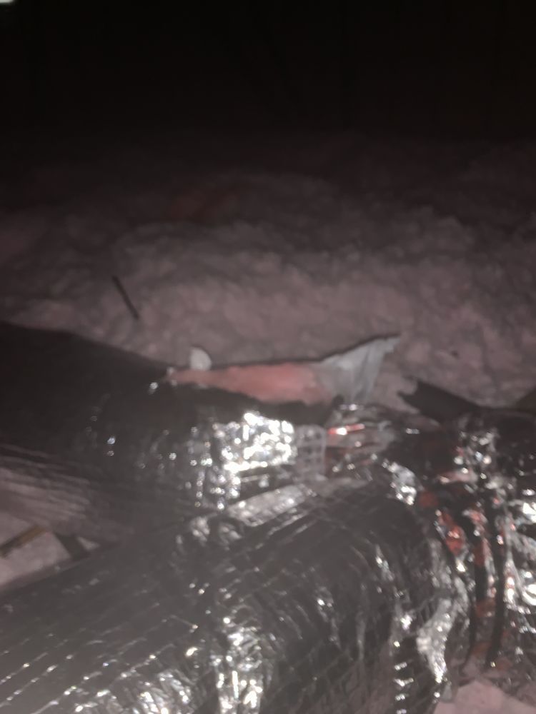 Black insulated ductwork in attic with insulation.