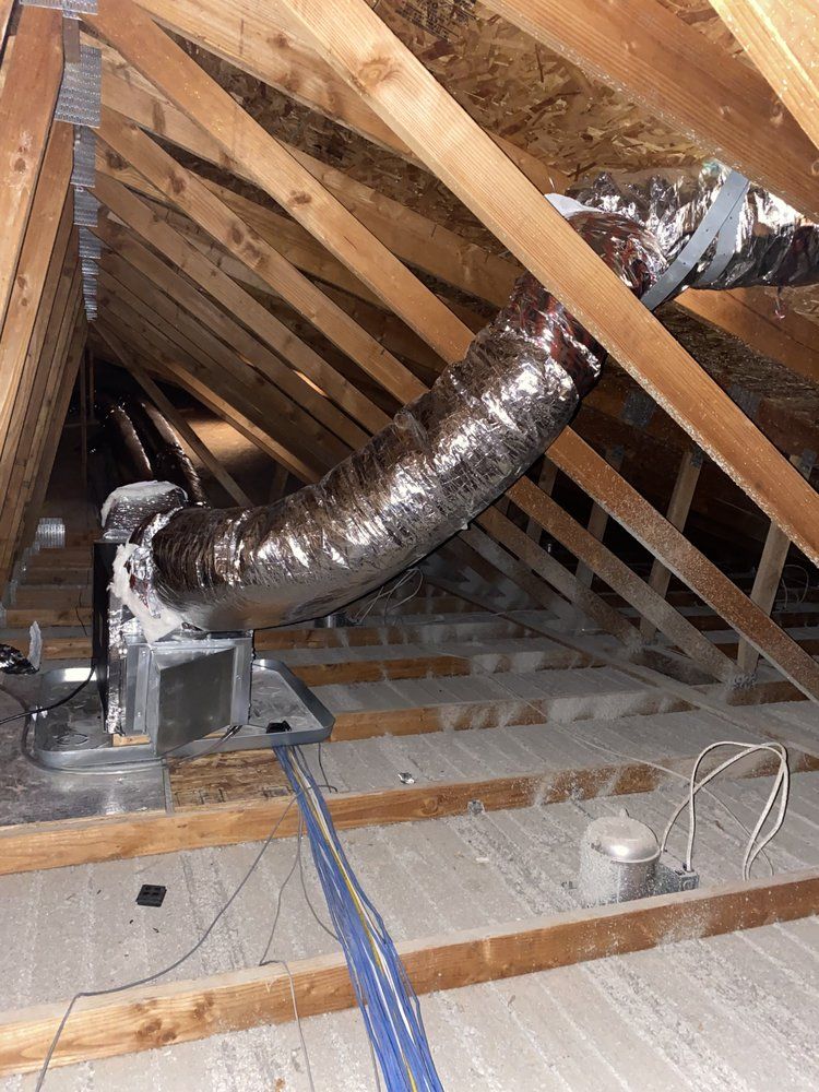 HVAC unit in an attic, with insulated ductwork. Wooden rafters and beams.