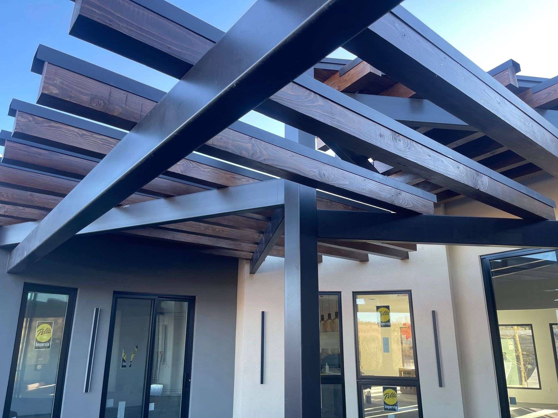 A house with a pergola on top of it and a lot of windows.