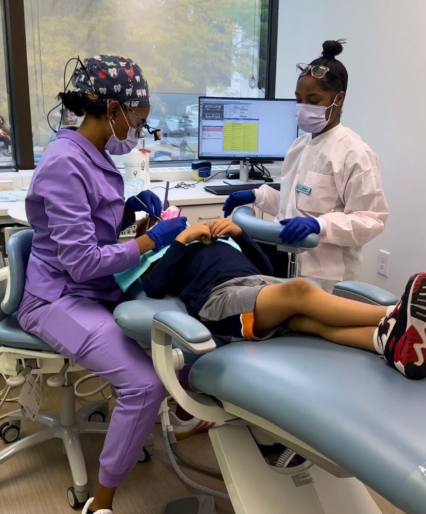 Two dentists are working on a child in a dental chair