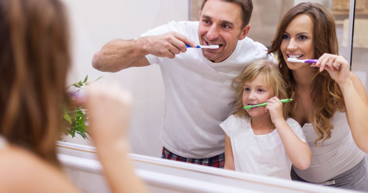Parents helping their child brush teeth at home to support kids’ healthy teeth and good oral hygiene