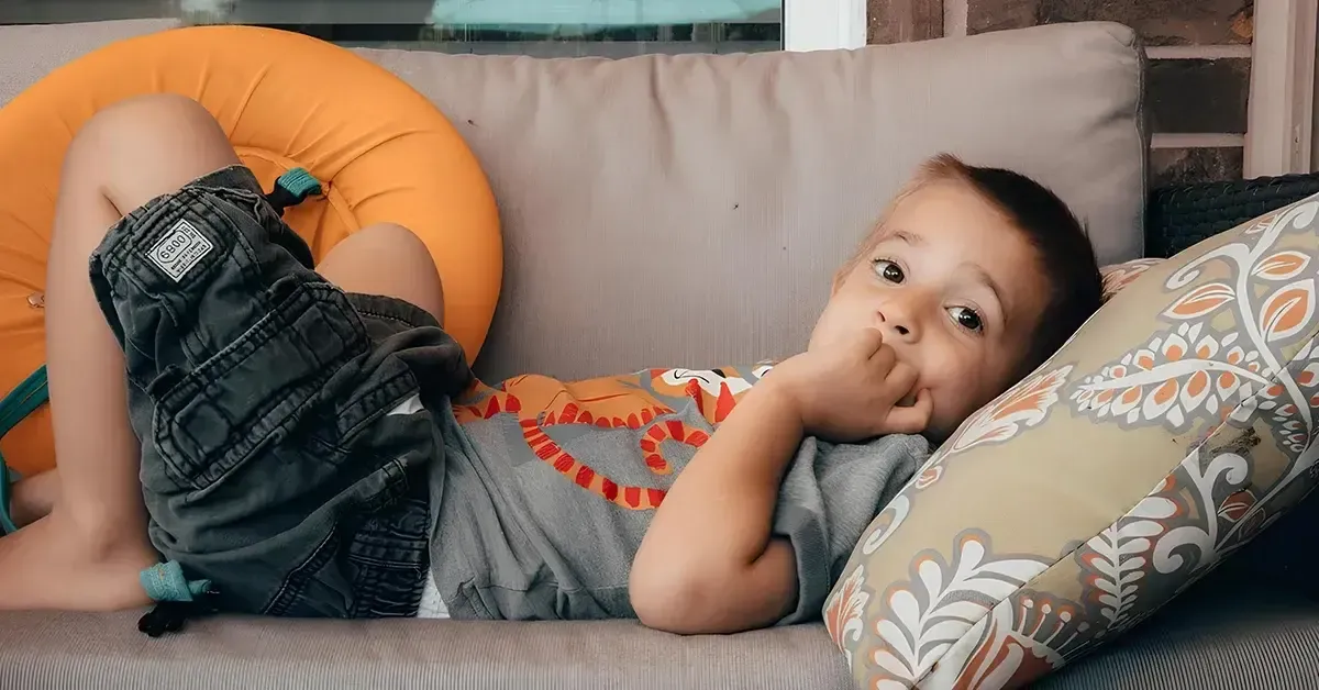 Young child sitting on a couch and sucking his thumb for comfort 