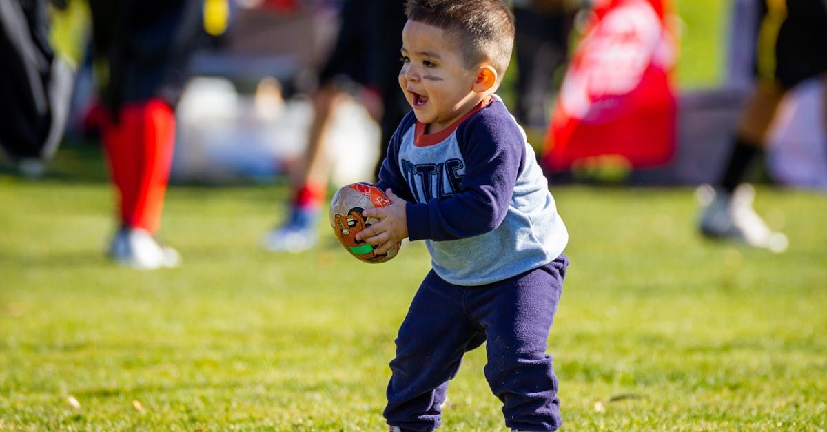 A little boy is playing with a ball on a field.