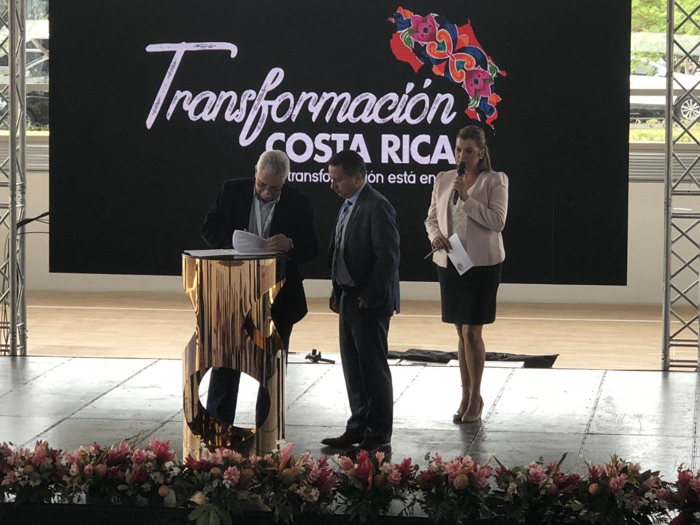 A group of people standing on a stage in front of a sign that says transformacion costa rica