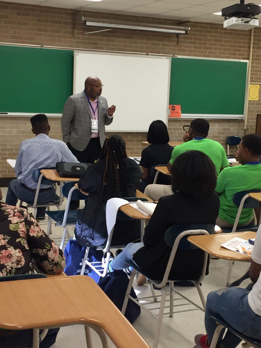 A man is giving a presentation to a group of students in a classroom