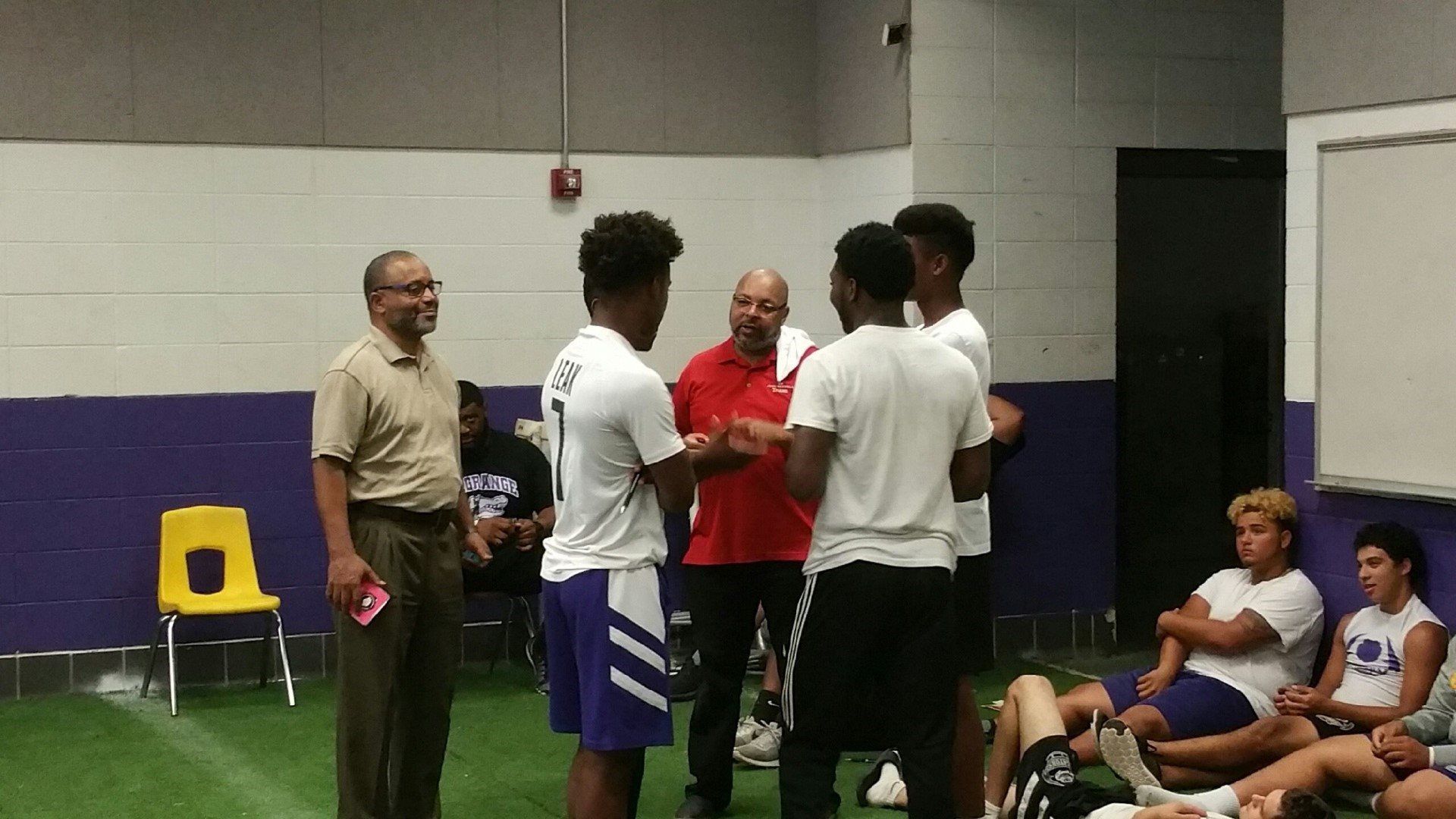 A group of young men are standing in a room talking to each other