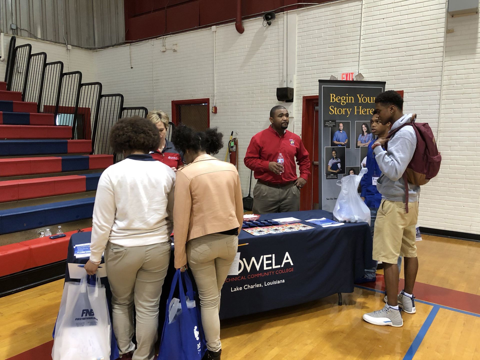 A group of people are standing around a table in a gym.