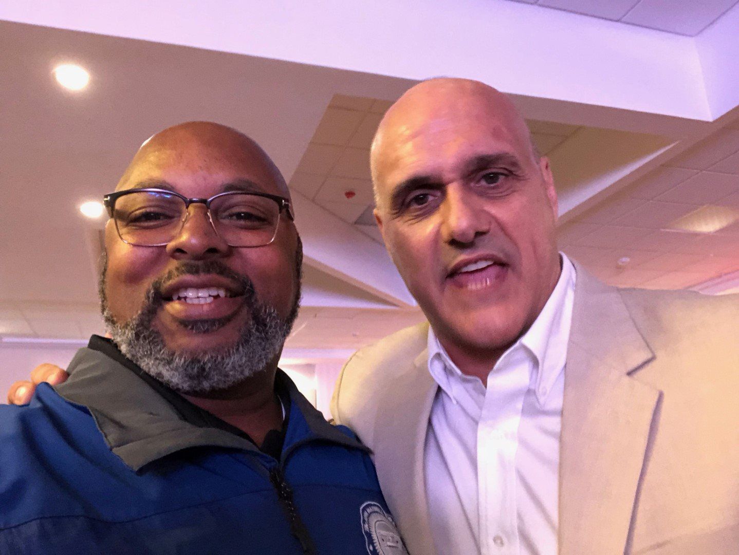 Two men are posing for a picture together in a room.