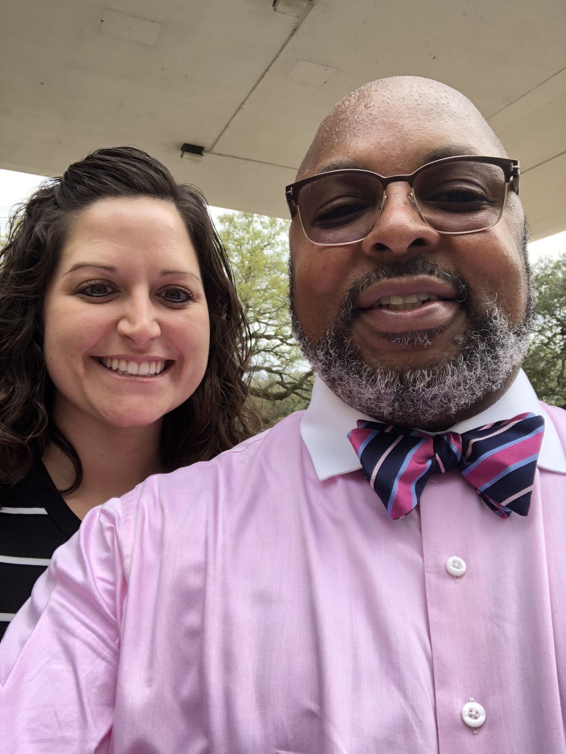 A man in a pink shirt and bow tie is standing next to a woman.
