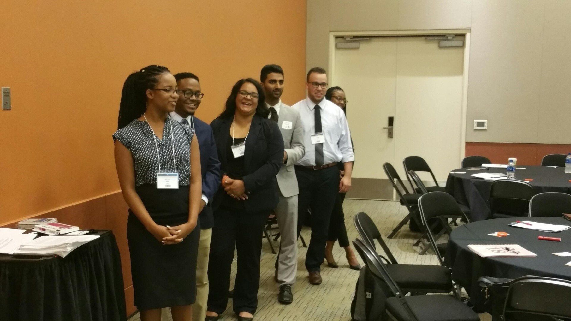 A group of people standing in a room with tables and chairs