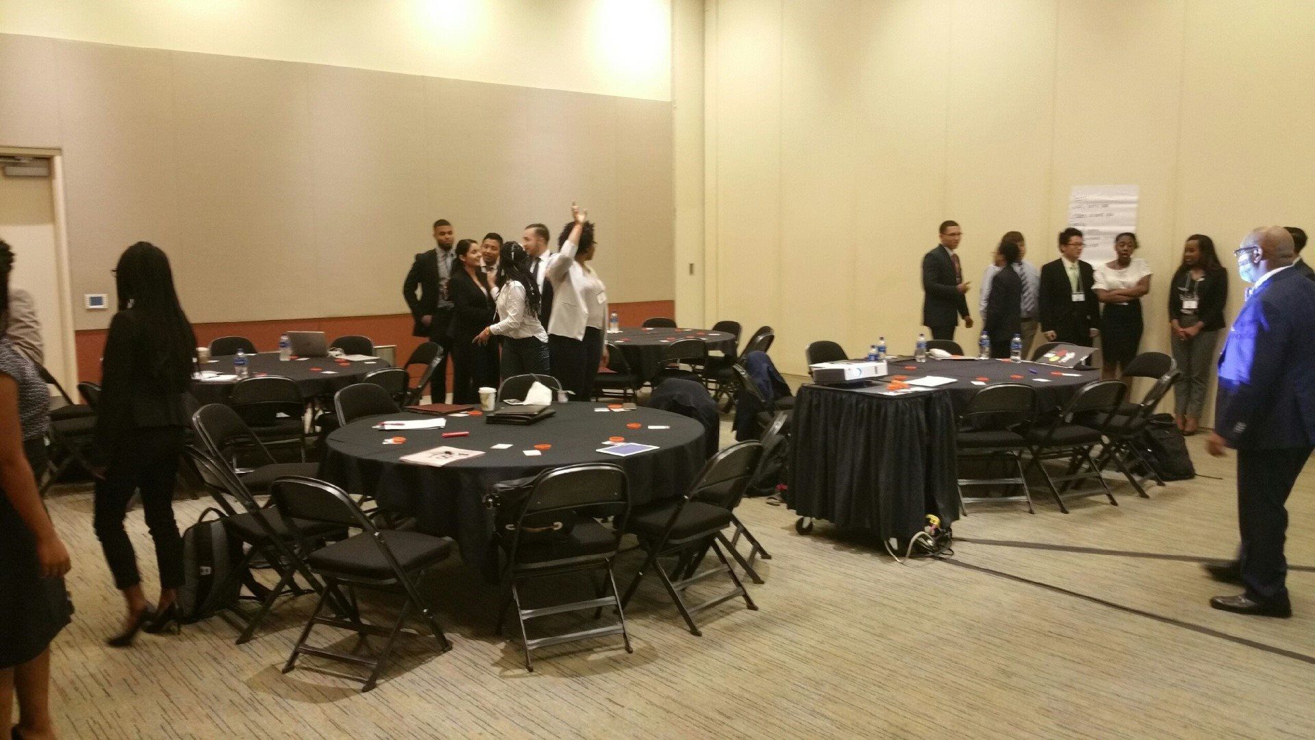 A group of people are standing around tables in a room.