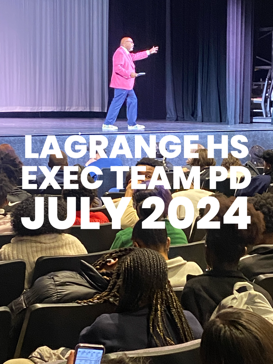 A man is standing on a stage giving a presentation to a group of people.