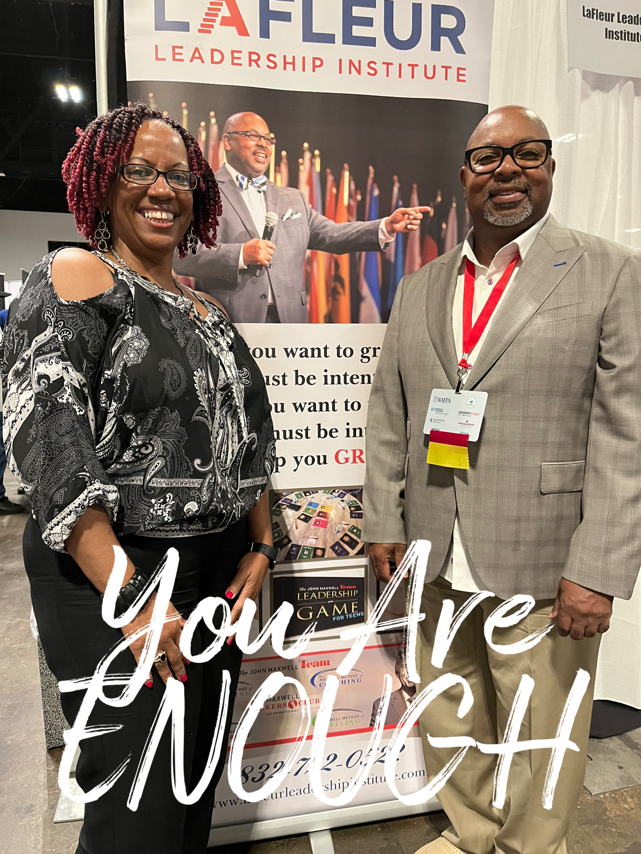 A man and a woman are standing next to each other in front of a sign that says `` you are enough ''.