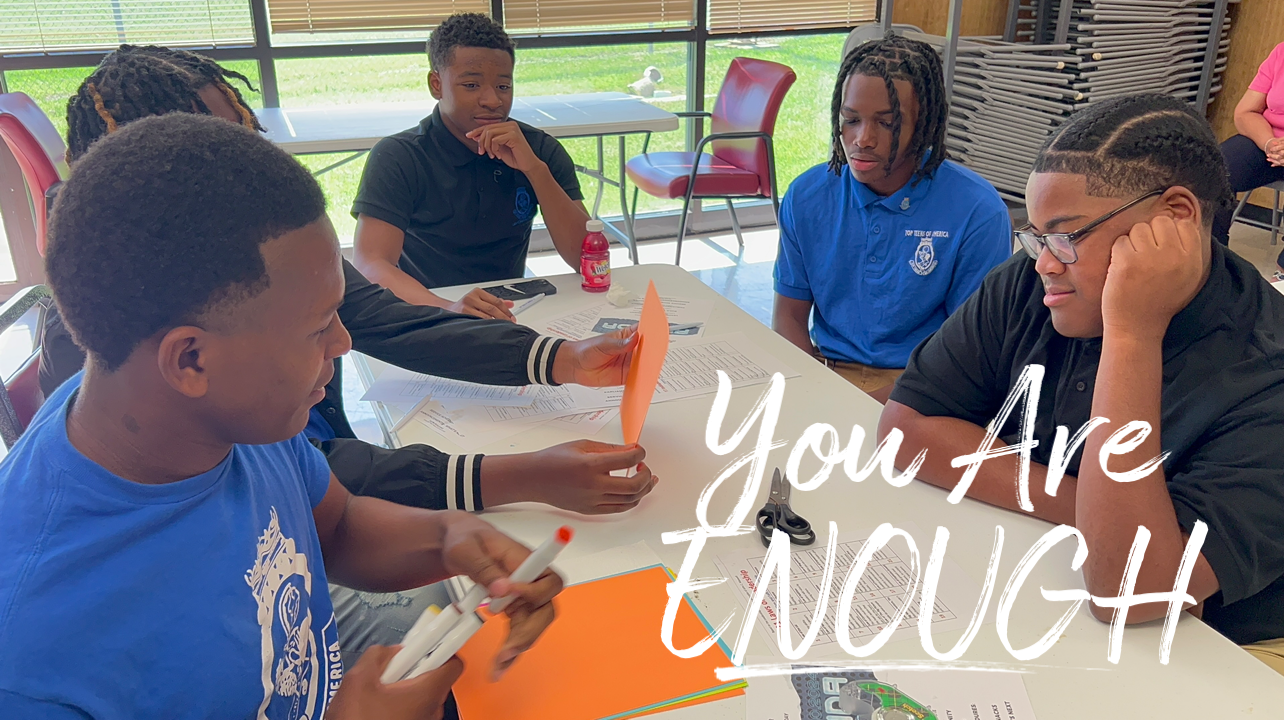 A group of young men are sitting around a table.