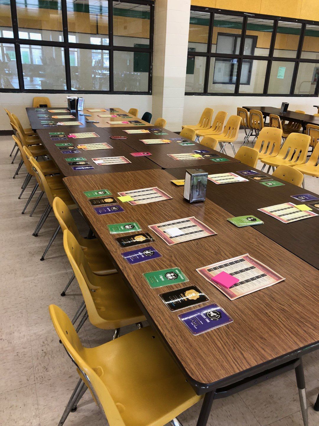 A long table with yellow chairs in a school cafeteria.