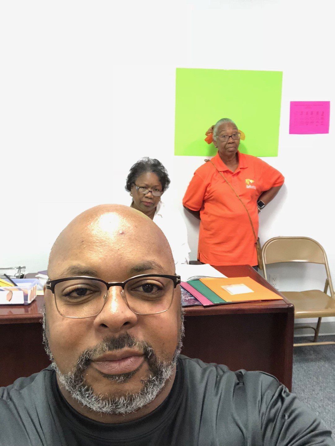 A man taking a selfie with two women behind him