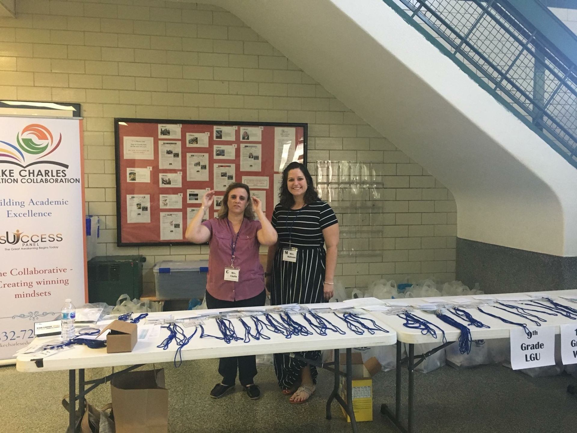 Two women are standing behind a table in front of a sign that says ' ep ' on it