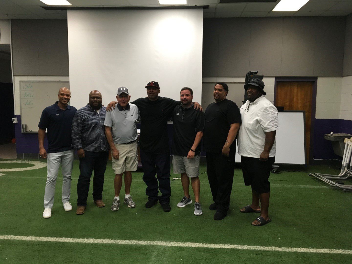 A group of men are posing for a picture on a football field.