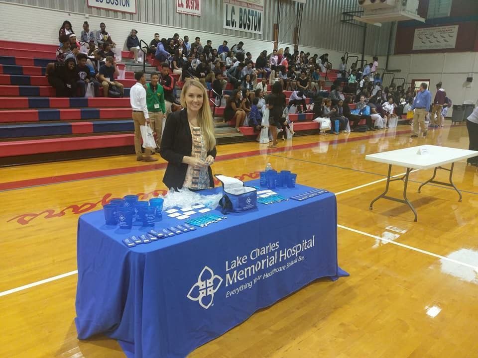 A woman stands behind a table that says lake charles memorial hospital