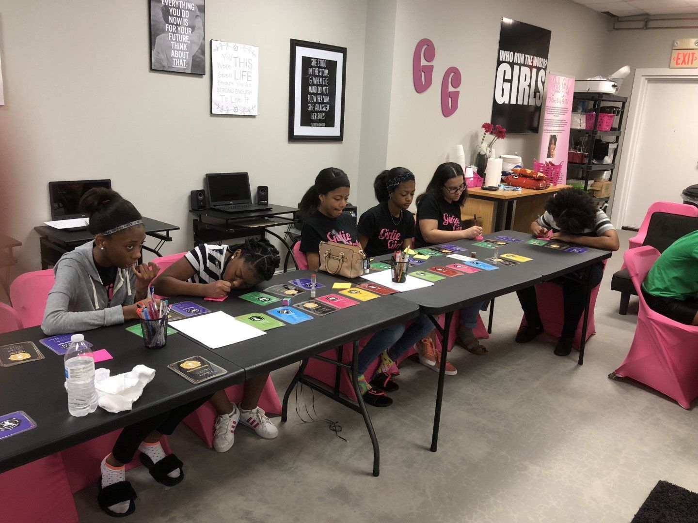 A group of young girls are sitting at tables in a room.