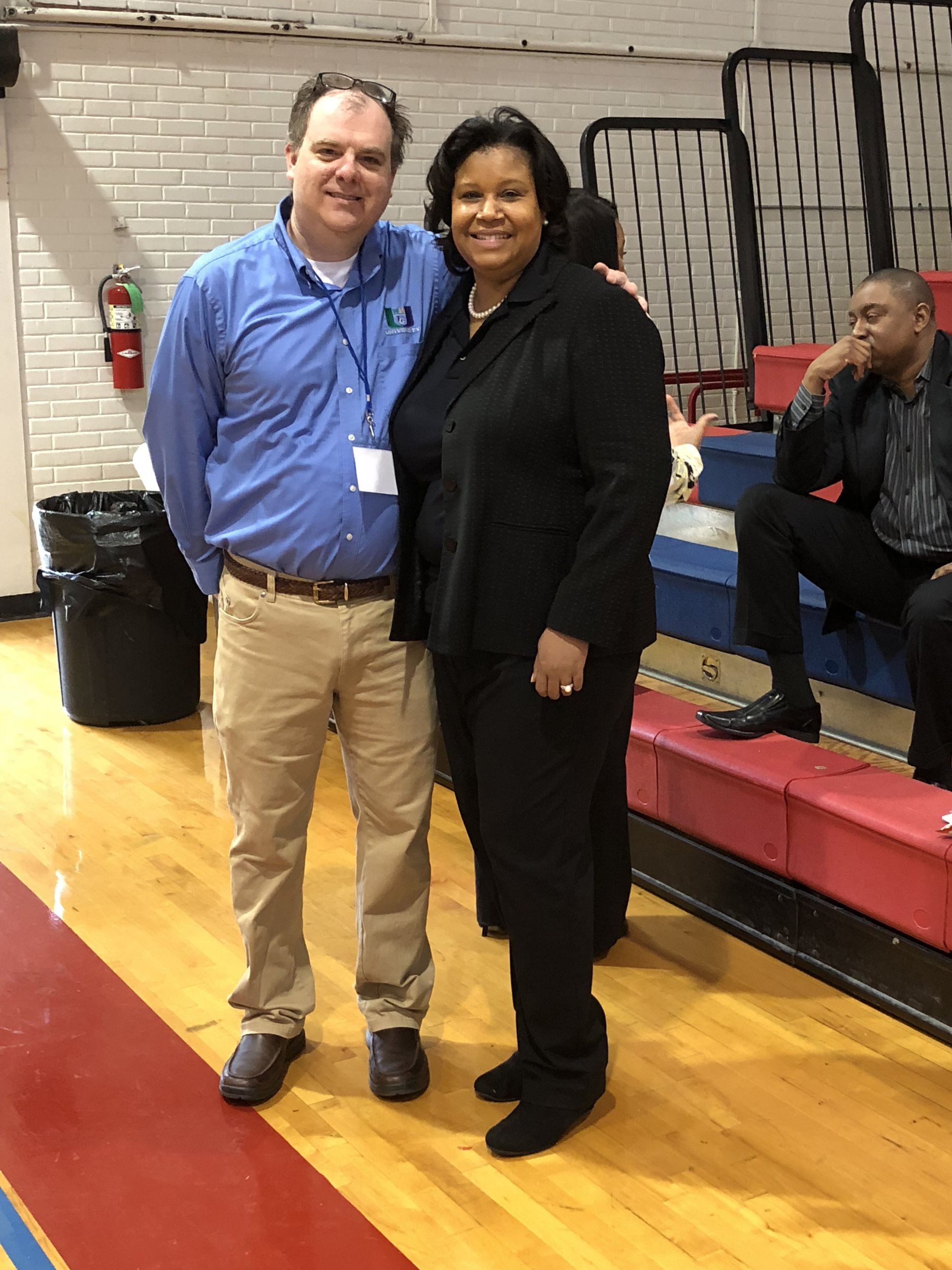 A man and a woman are posing for a picture on a basketball court.