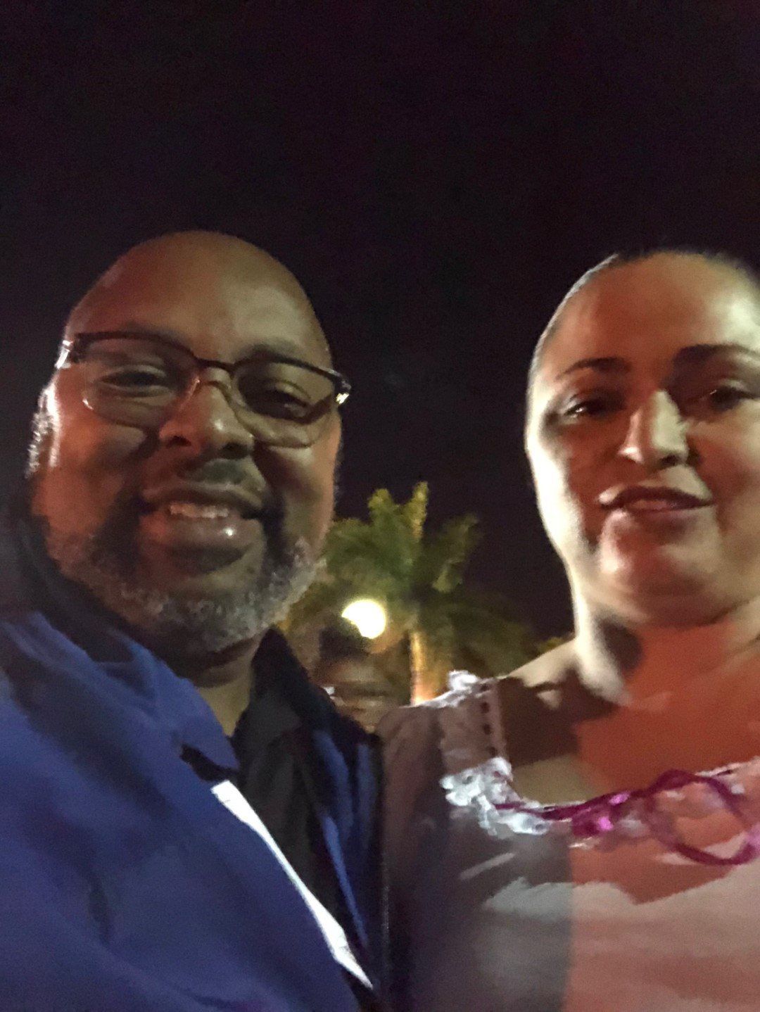 A man and a woman are posing for a picture at night