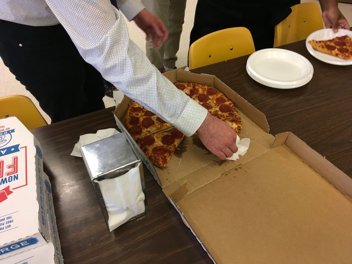 A person is taking a slice of pepperoni pizza out of a box