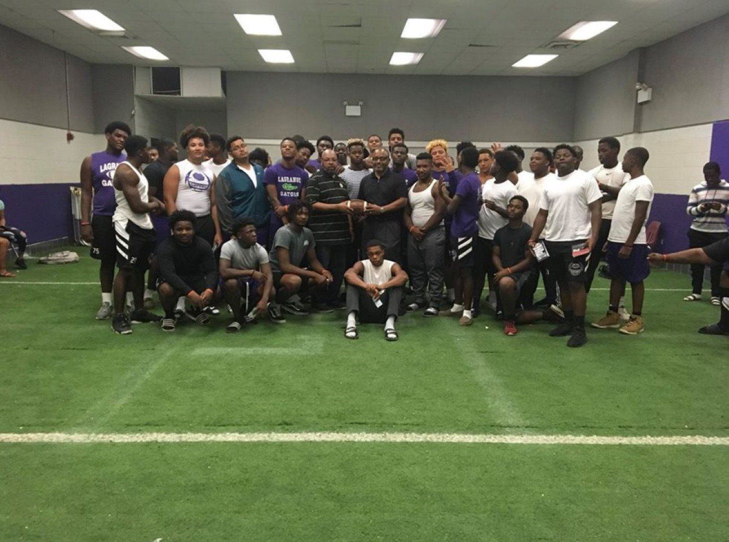 A group of people are posing for a picture in a gym.