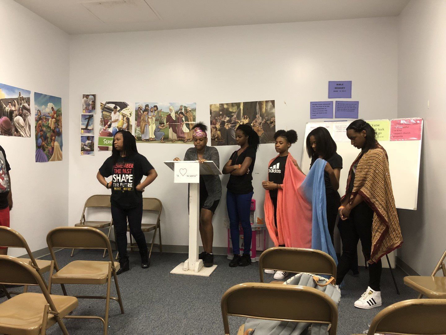 A group of women are standing in a room with folding chairs.