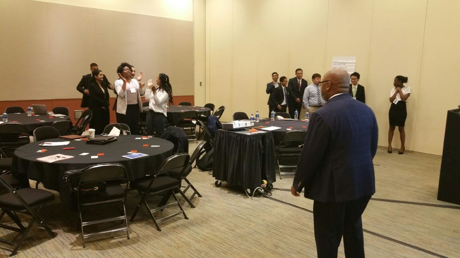 A man in a suit is standing in a room with tables and chairs.