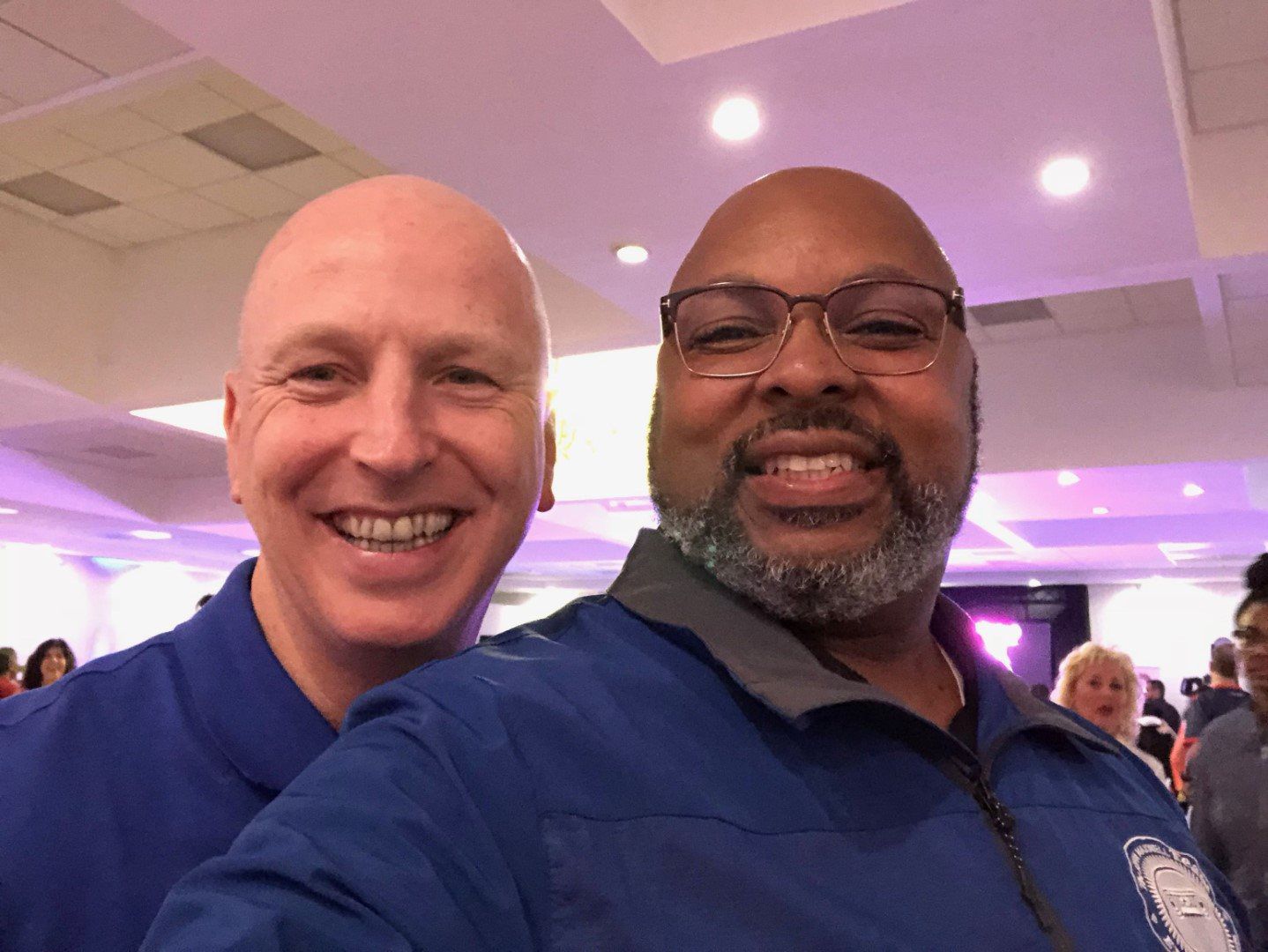 Two men are posing for a picture together in a room.