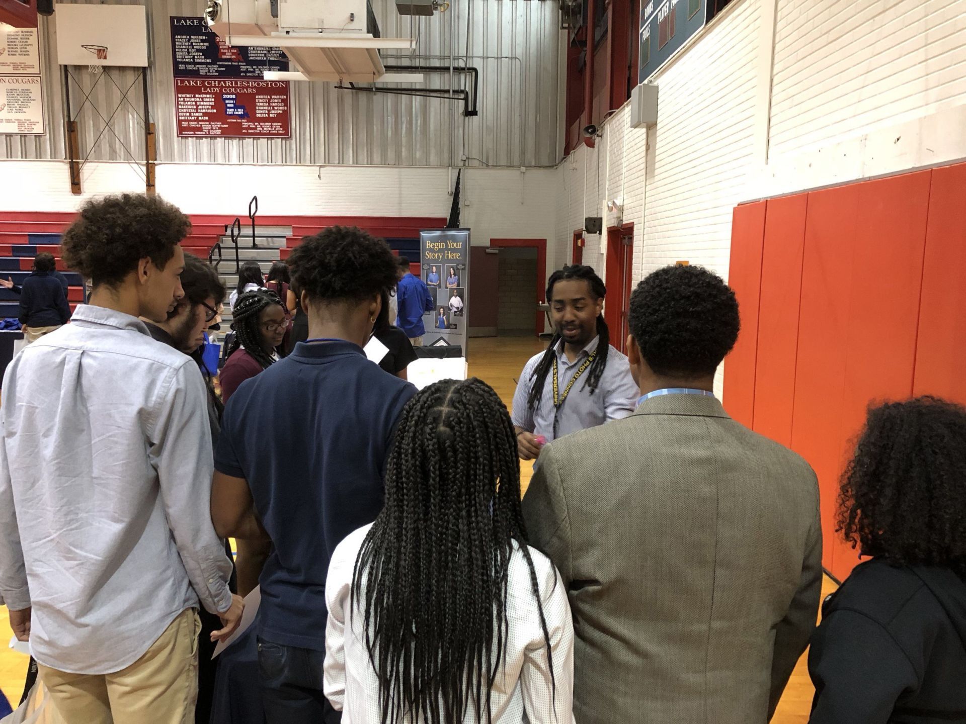 A group of people are standing in a gym talking to each other.