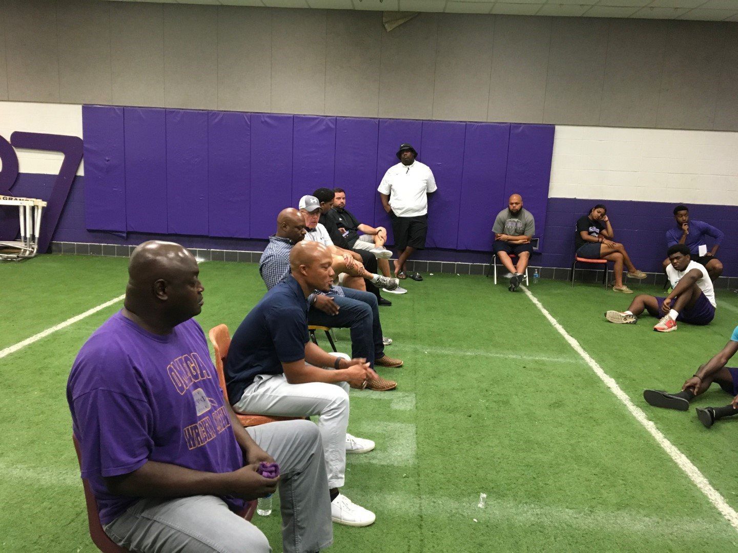 A group of men are sitting in chairs on a football field.