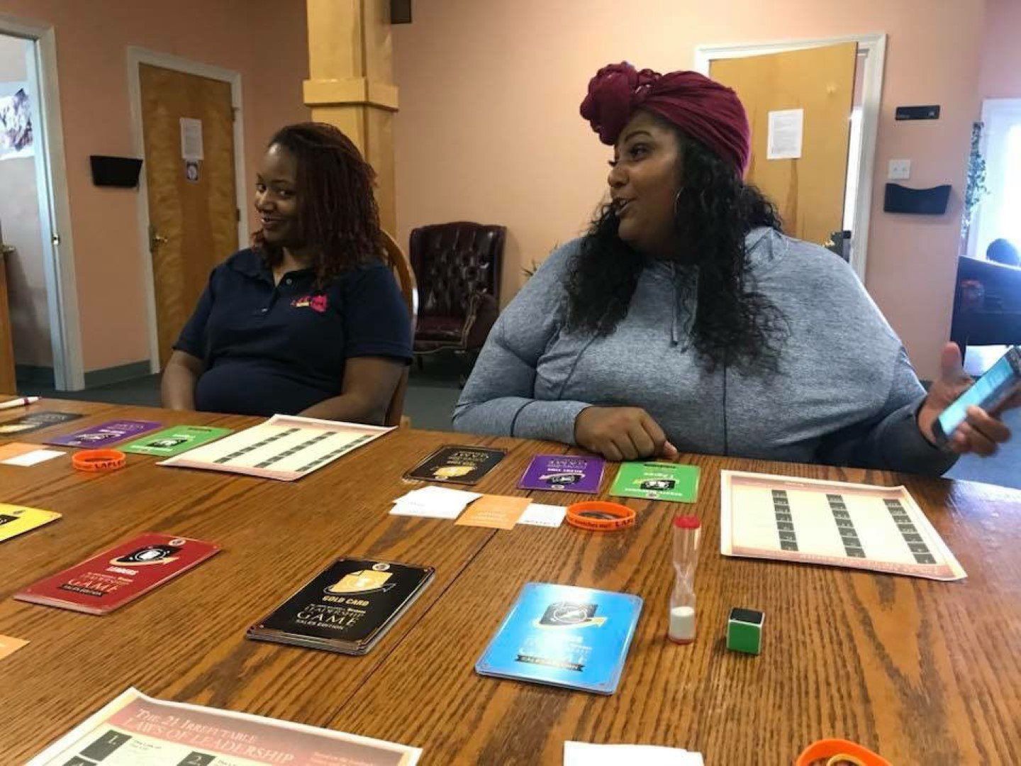 Two women are sitting at a table playing a board game.