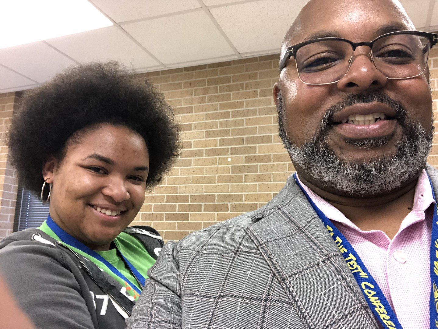 A man and a woman are posing for a picture in front of a brick wall.