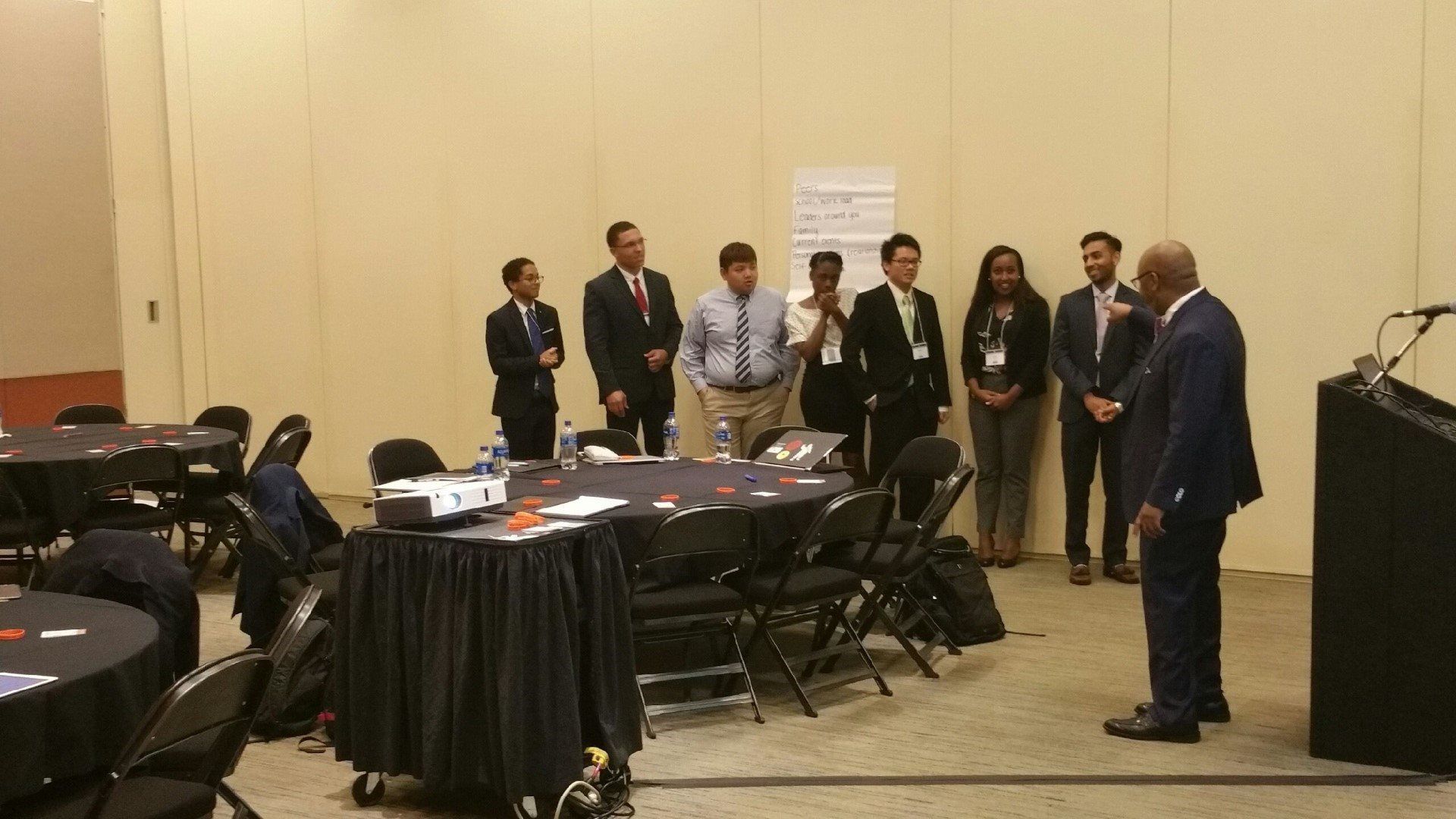 A group of people are standing around a podium in a conference room.