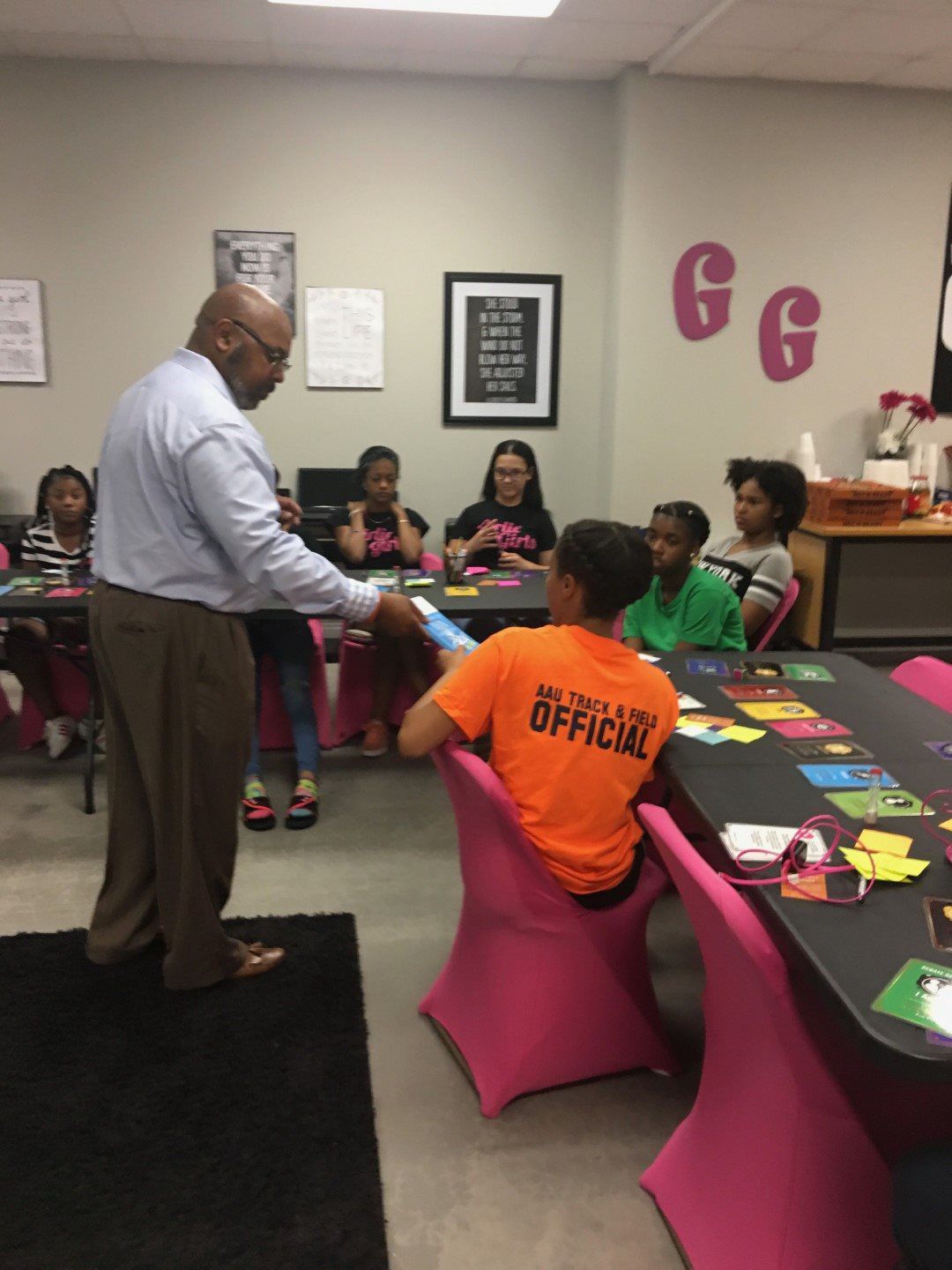 A man is giving a presentation to a group of children who are sitting at tables