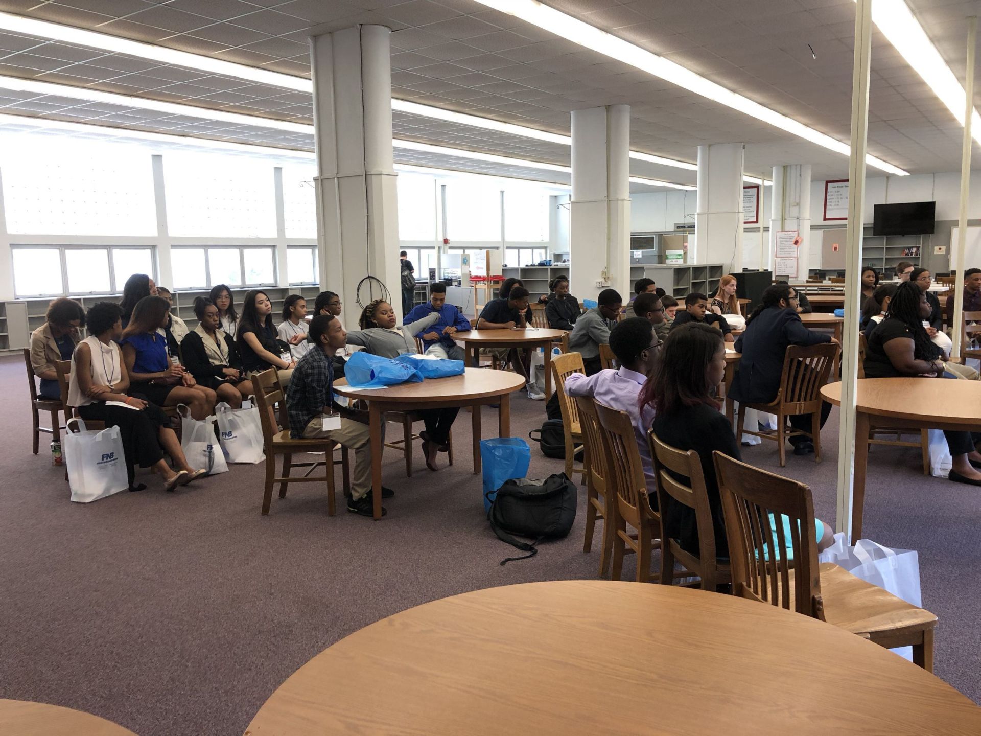 A group of people are sitting at tables in a library.