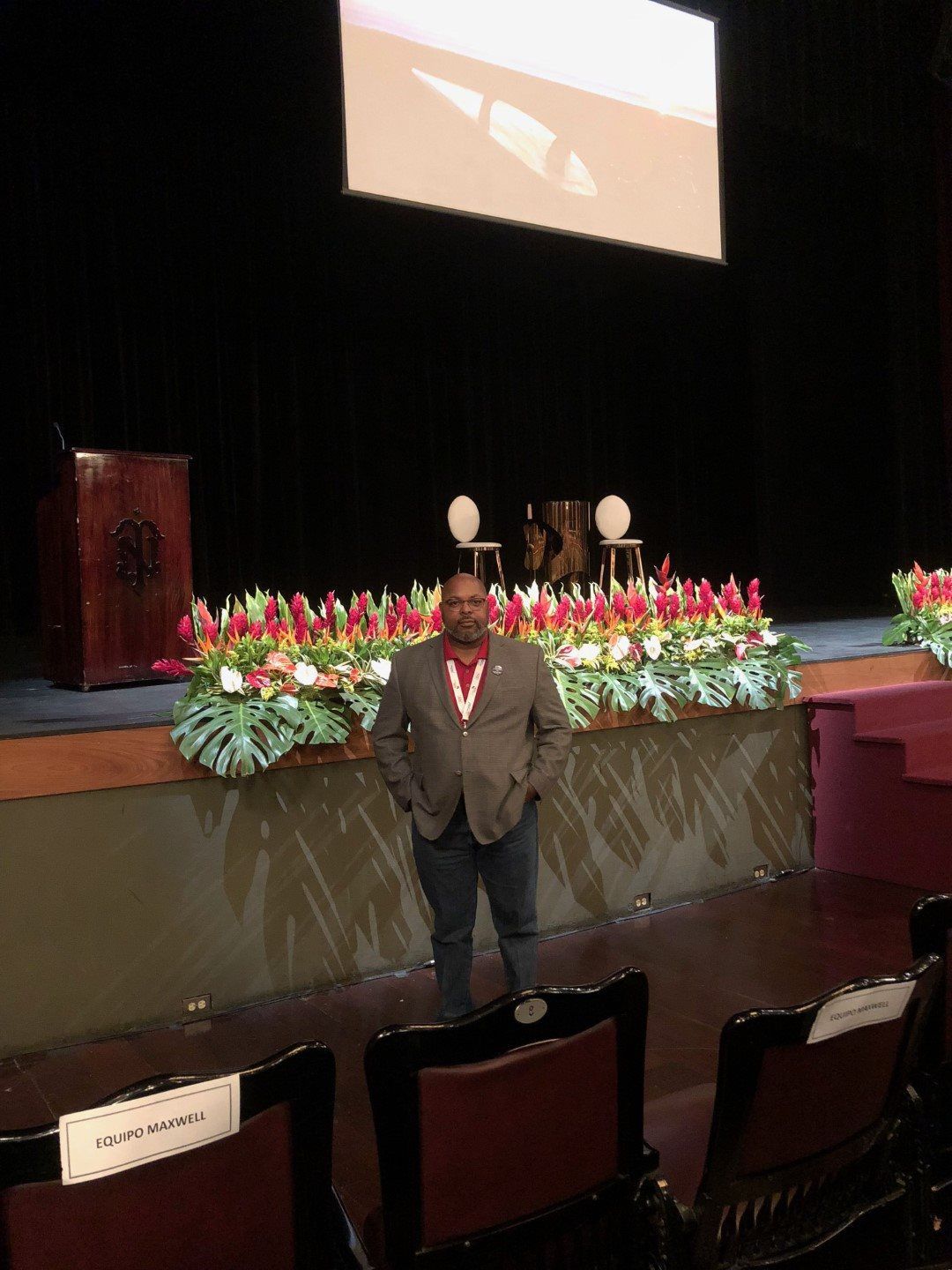 A man is standing on a stage in front of a large screen.