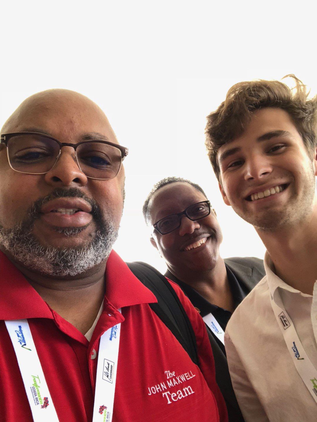A man in a red shirt is posing for a picture with two other people.
