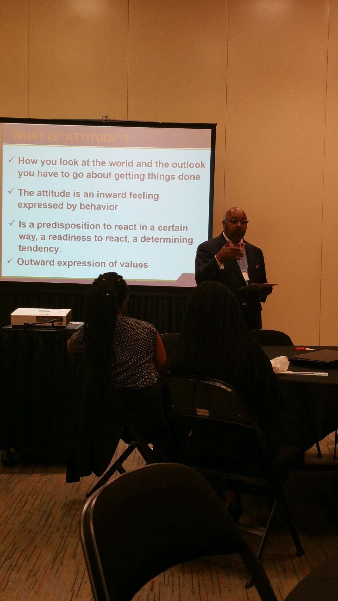 A man is giving a presentation to a group of people in front of a large screen.