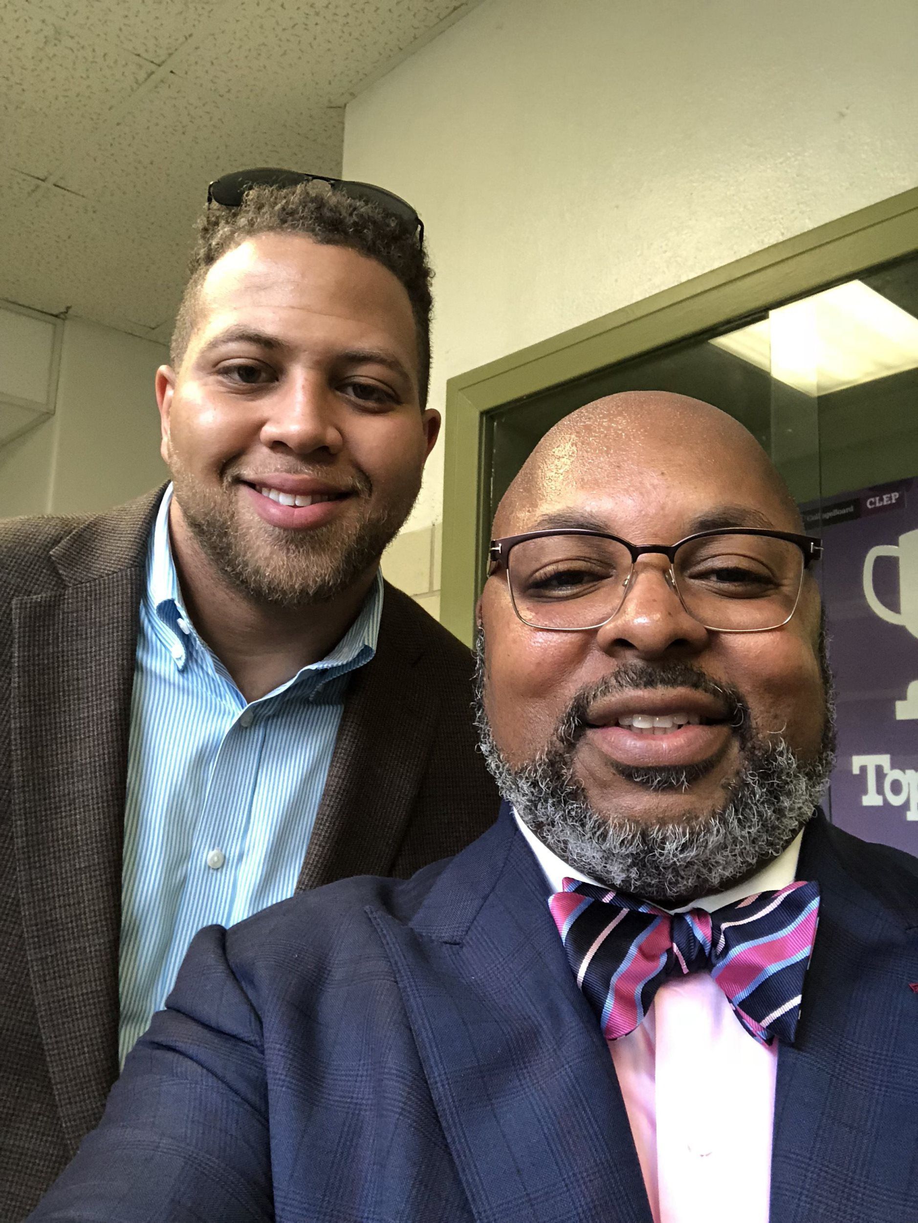 Two men in suits and bow ties are posing for a picture.