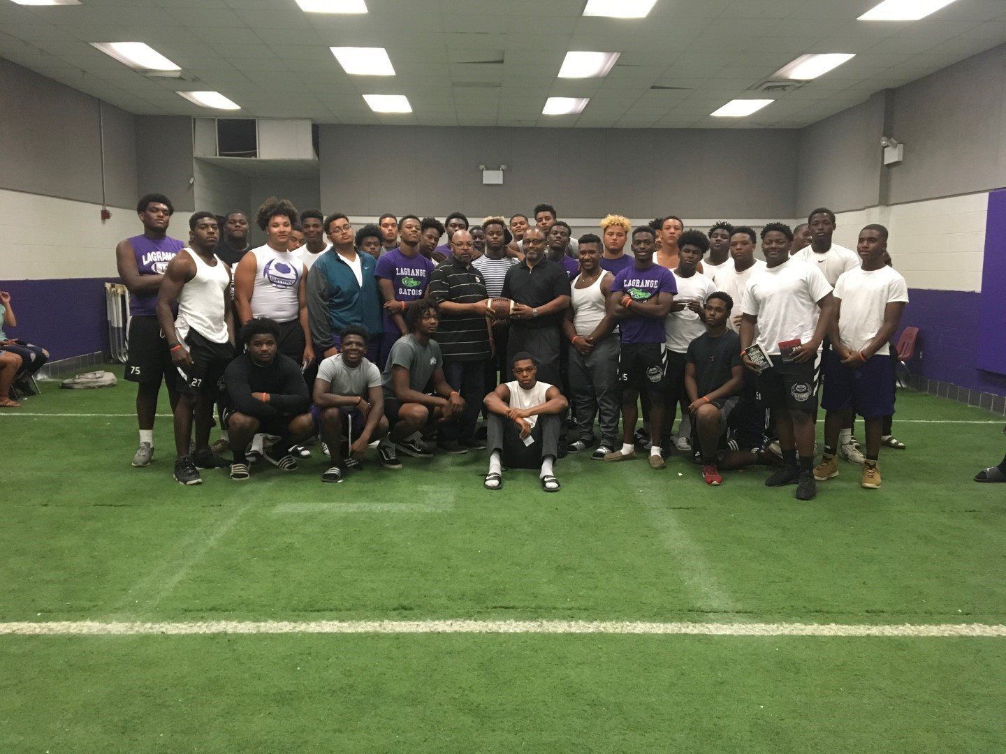 A group of people are posing for a picture in a gym.