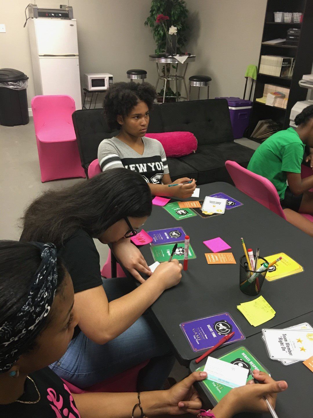 A girl in a new york shirt sits at a table with other people