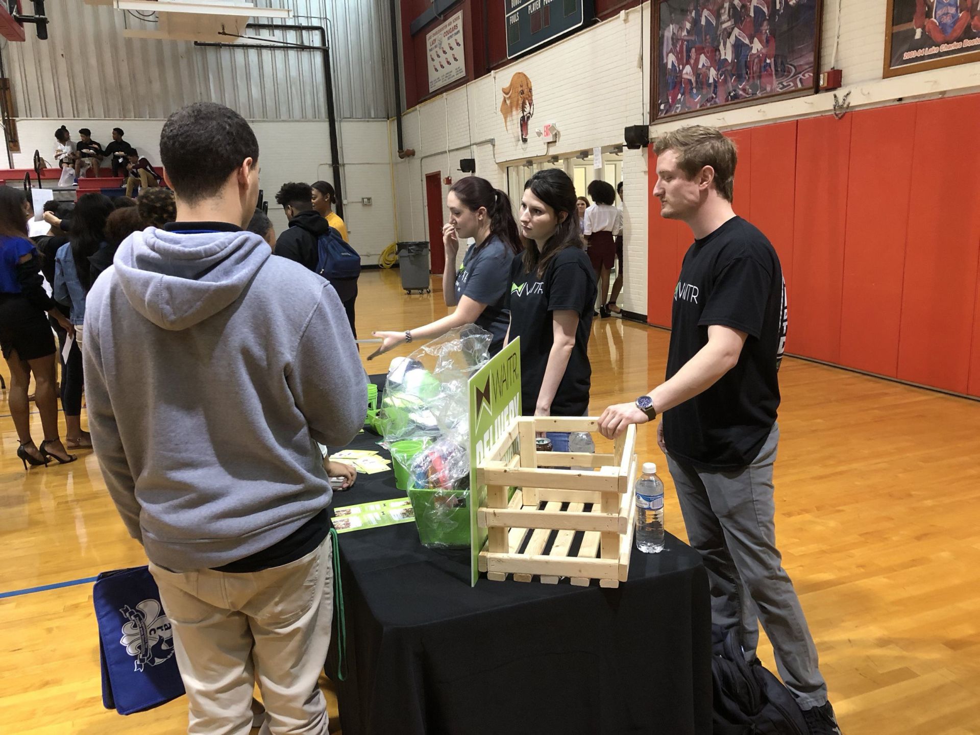 A group of people are standing around a table in a gym.